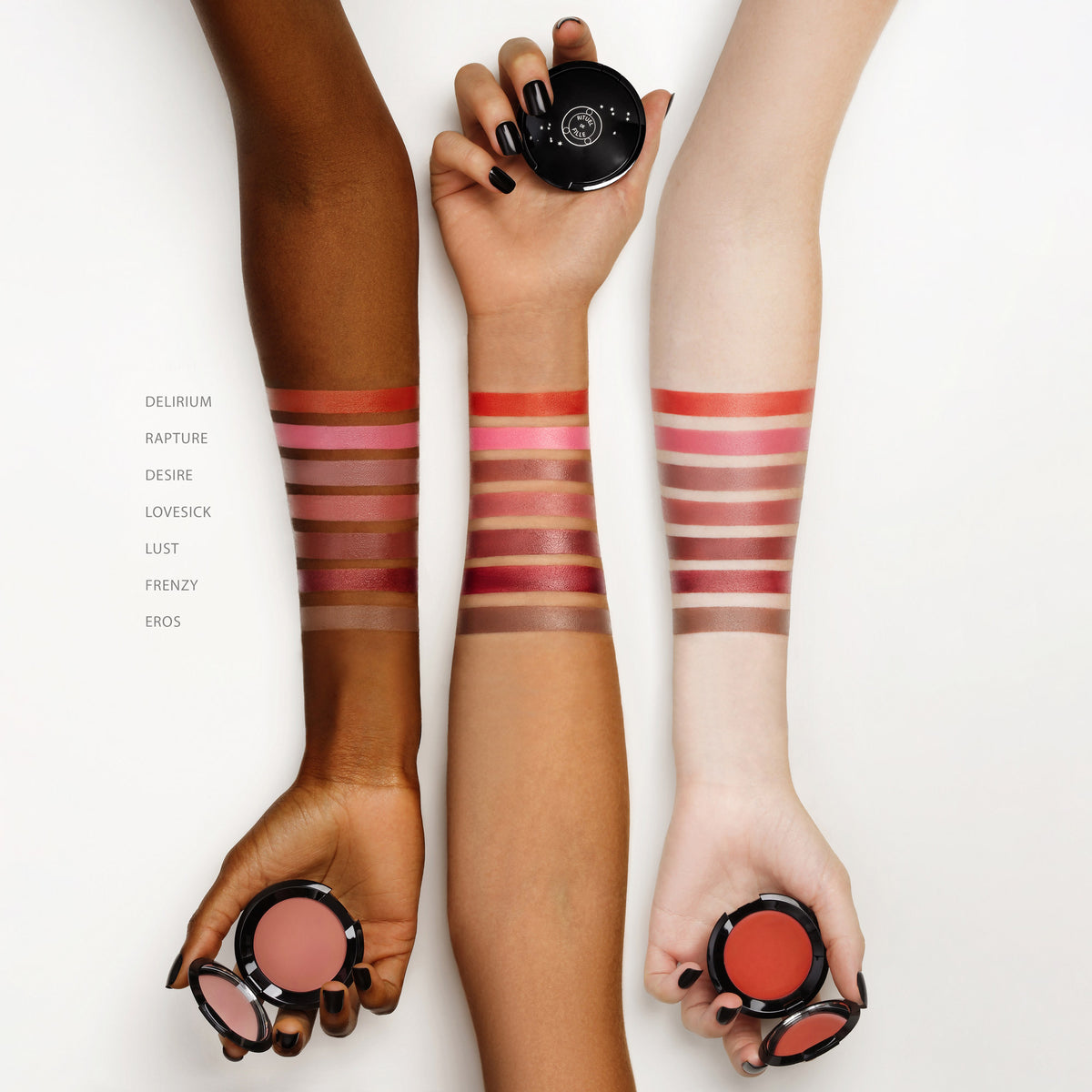 Three hands with makeup swatches on wrists holding a compact