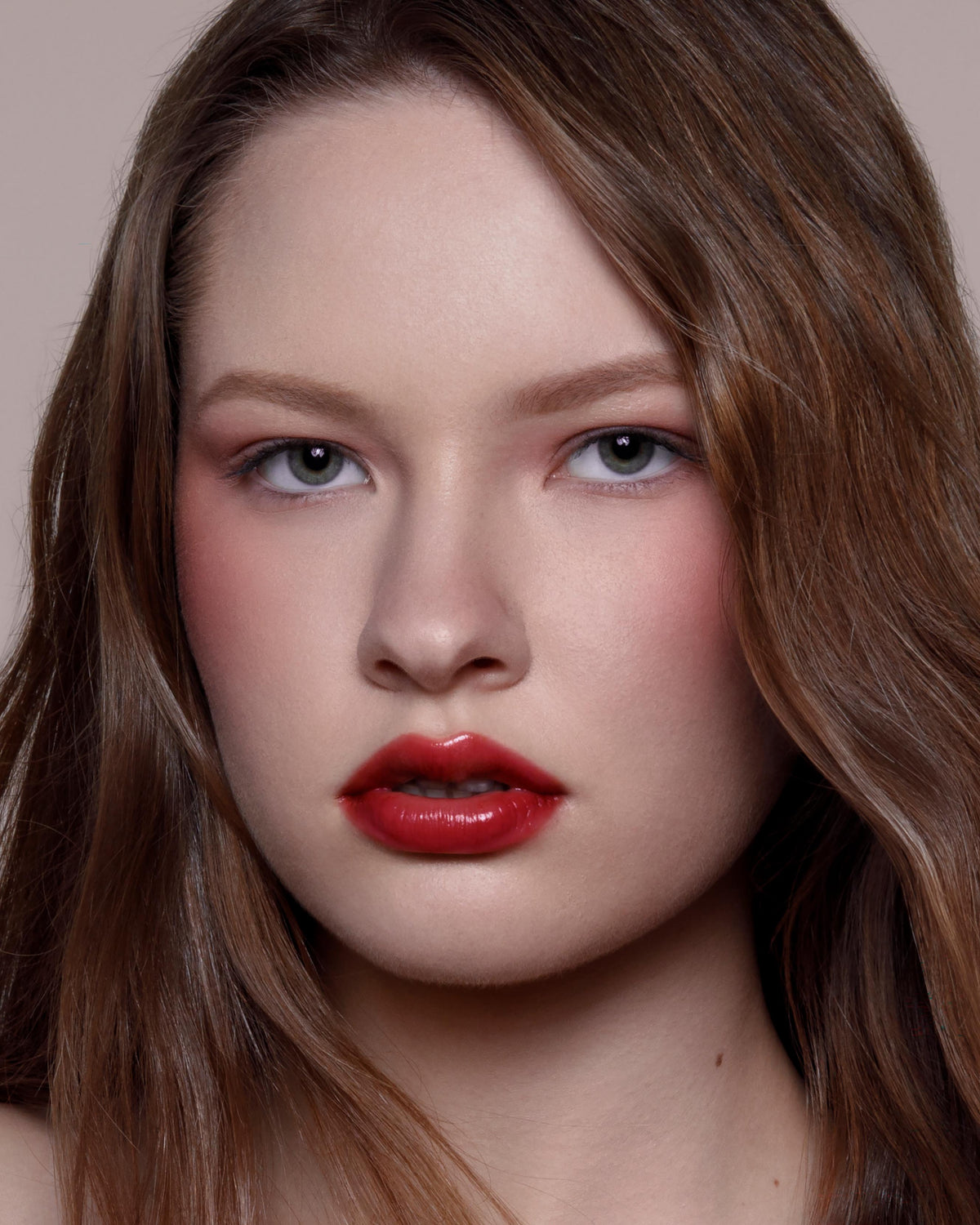 Close-up of a model with fair skin wearing red lip and cheek makeup