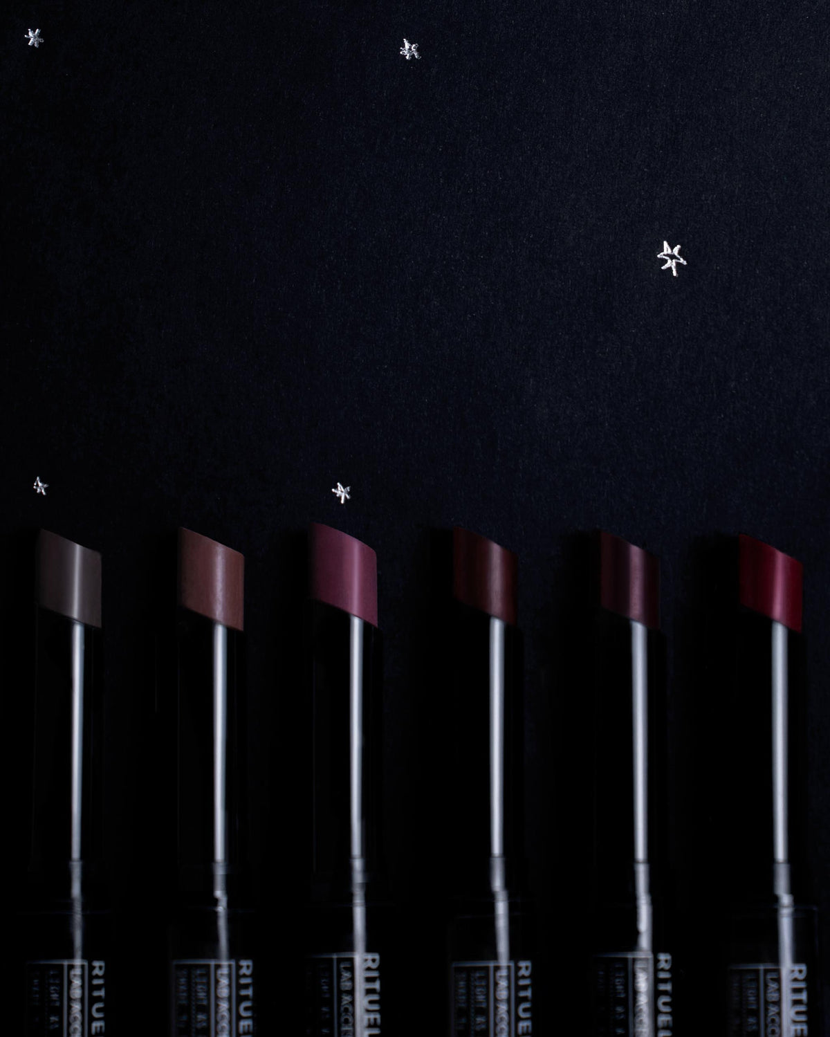 Set of Rituel de Fille lipsticks on a dark background with silver hand-drawn stars